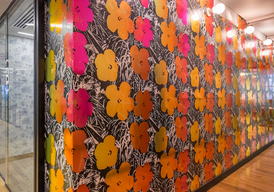 Warhol Flowers in Golden Shower brightens up any space including this hallway. You can see Brooklyn Toile in custom soft blue peeking out of the conference room as well.