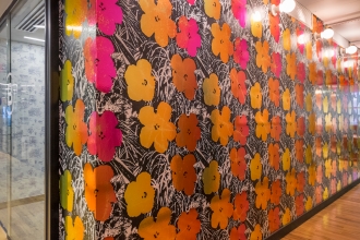 Warhol Flowers in Golden Shower brightens up any space including this hallway. You can see Brooklyn Toile in custom soft blue peeking out of the conference room as well.